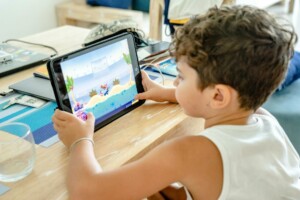a boy in white tank top playing on a tablet