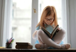 girl in blue dress reading a book