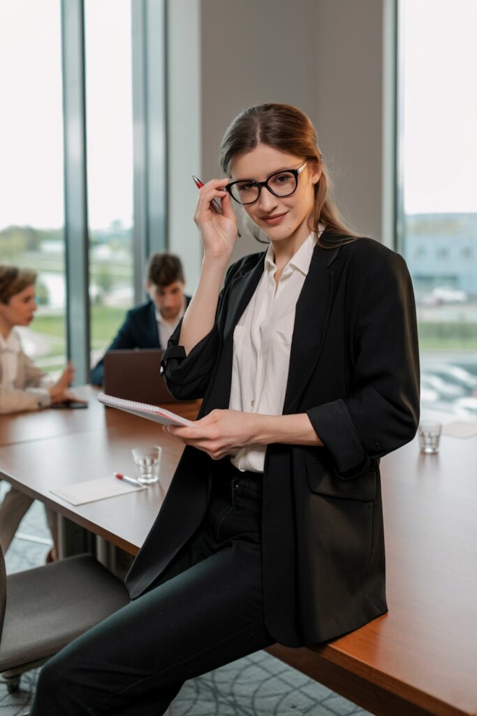 woman in black blazer and pants sitting at wooden table